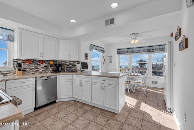 kitchen featuring visible vents, backsplash, dishwasher, and light countertops