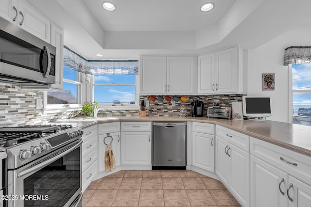 kitchen featuring decorative backsplash, white cabinets, and stainless steel appliances