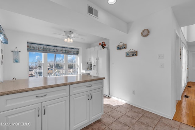 kitchen with visible vents, white cabinets, a ceiling fan, and white fridge with ice dispenser