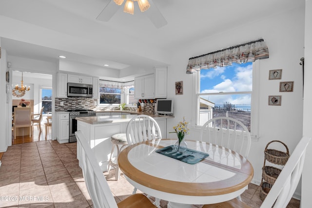 dining area with light tile patterned floors, ceiling fan with notable chandelier, and recessed lighting