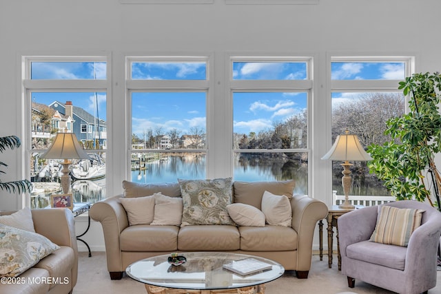 living area featuring light carpet and a water view