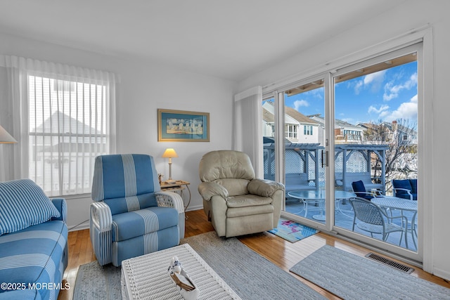 living area featuring visible vents, baseboards, and wood finished floors