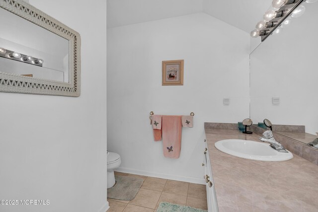 bathroom featuring tile patterned floors, toilet, baseboards, vanity, and vaulted ceiling