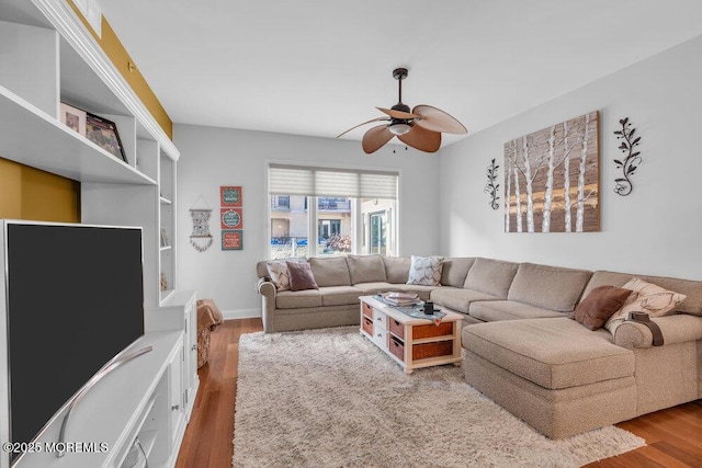 living area with baseboards, a ceiling fan, and wood finished floors