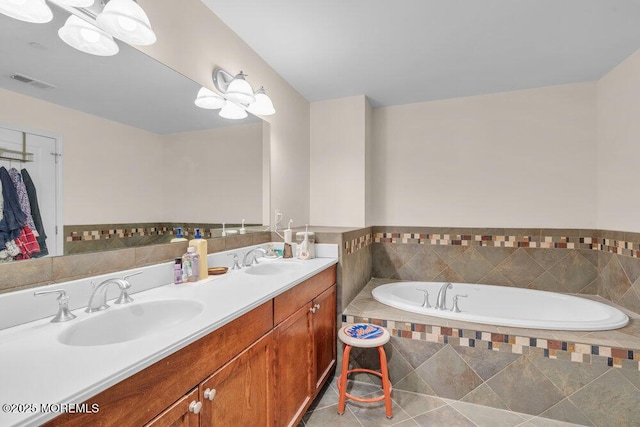 full bath with tile patterned floors, double vanity, a garden tub, and a sink