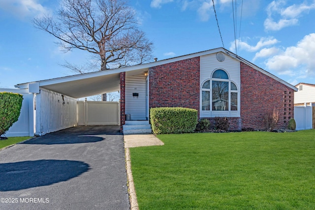 mid-century inspired home featuring an attached carport, a front yard, fence, driveway, and brick siding