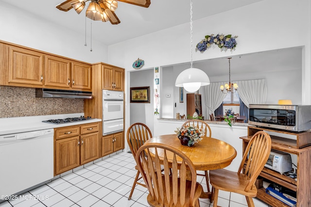 kitchen with a warming drawer, under cabinet range hood, backsplash, appliances with stainless steel finishes, and light countertops