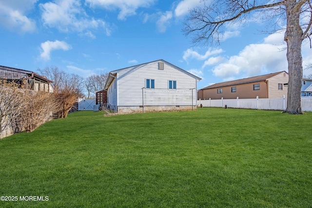 back of house with crawl space, a lawn, and fence