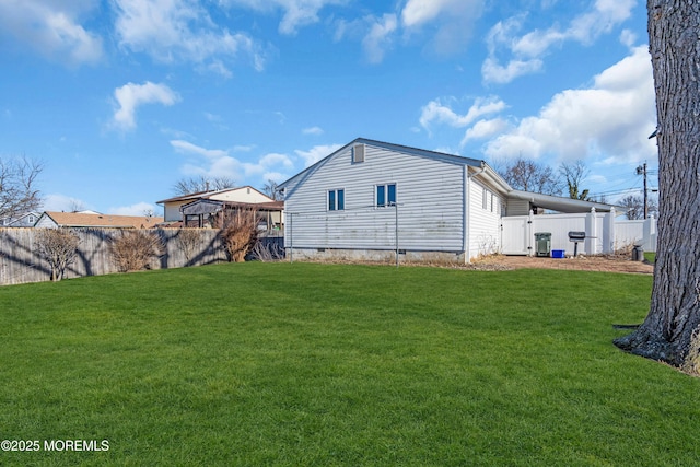 back of property with a lawn, fence, and crawl space