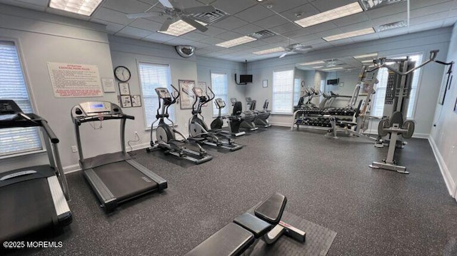 gym featuring a drop ceiling, baseboards, visible vents, and ceiling fan