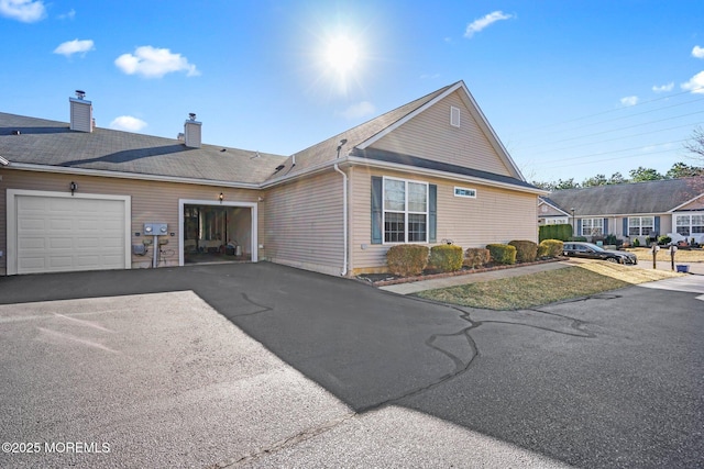 view of front of property featuring aphalt driveway, a chimney, and an attached garage