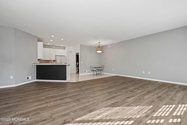 unfurnished living room with visible vents, baseboards, and wood finished floors