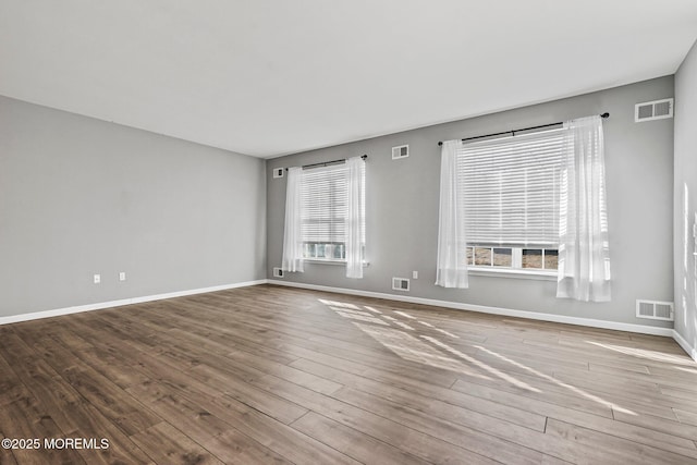 spare room featuring wood finished floors and visible vents