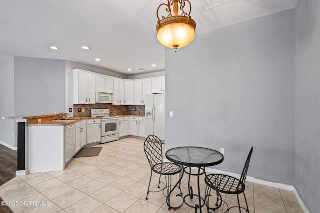 kitchen featuring a sink, tasteful backsplash, white cabinetry, white appliances, and baseboards