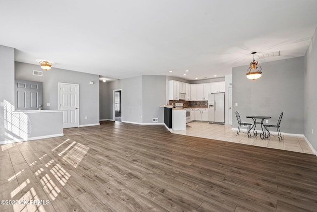 unfurnished living room featuring visible vents, recessed lighting, baseboards, and light wood finished floors