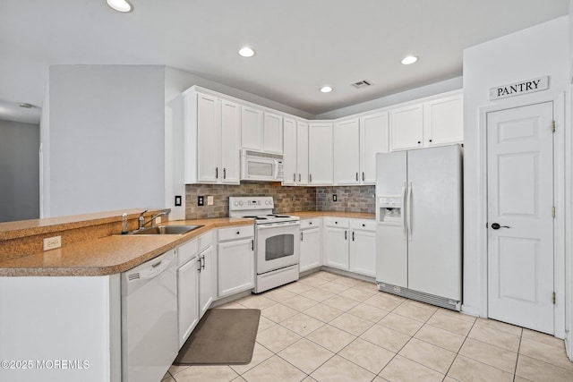 kitchen featuring a sink, backsplash, white appliances, a peninsula, and white cabinets