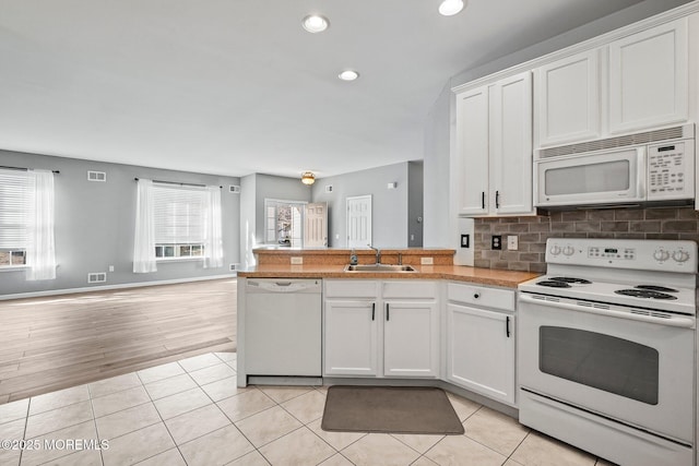 kitchen featuring a sink, white appliances, plenty of natural light, and light tile patterned flooring