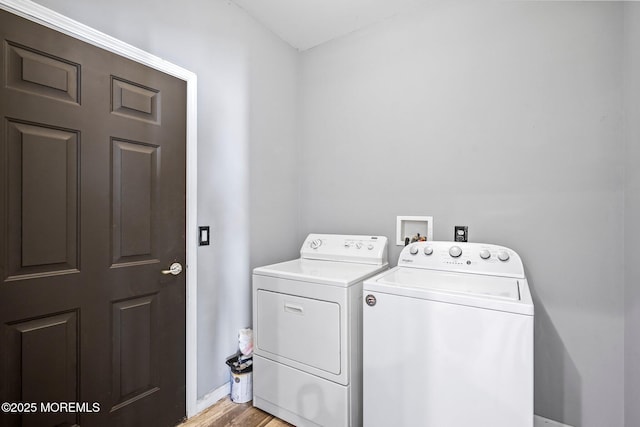 clothes washing area featuring laundry area, baseboards, light wood finished floors, and washer and clothes dryer