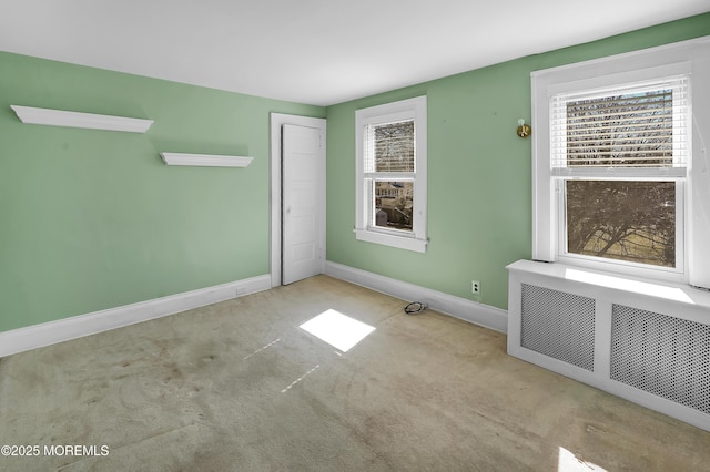 carpeted empty room featuring radiator and baseboards