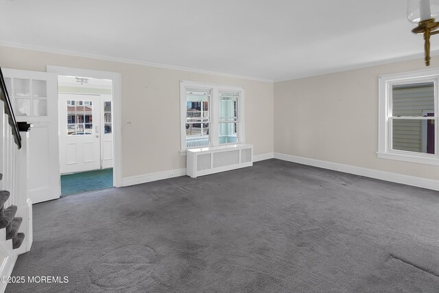 empty room with dark carpet, radiator, crown molding, and baseboards