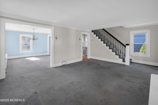 unfurnished living room with a notable chandelier, stairway, baseboards, and dark colored carpet