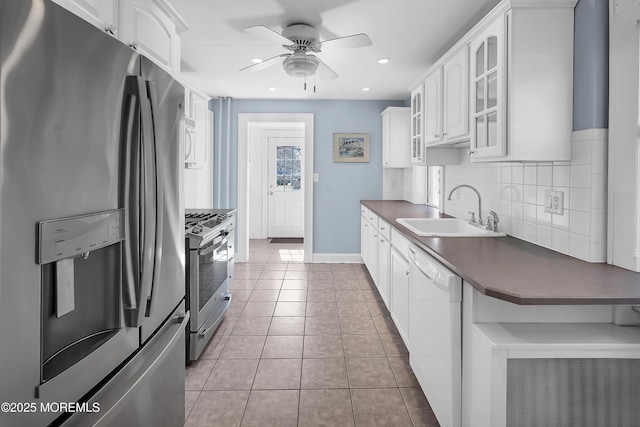 kitchen featuring dark countertops, glass insert cabinets, decorative backsplash, stainless steel appliances, and a sink