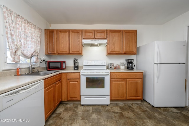 kitchen featuring under cabinet range hood, stone finish flooring, a sink, white appliances, and light countertops