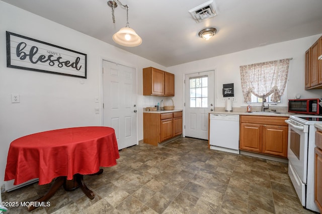 kitchen with white appliances, light countertops, visible vents, and a sink