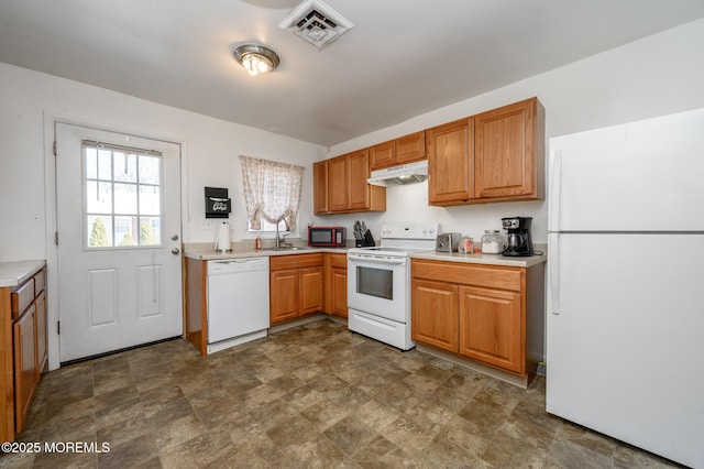 kitchen featuring visible vents, under cabinet range hood, a sink, white appliances, and light countertops