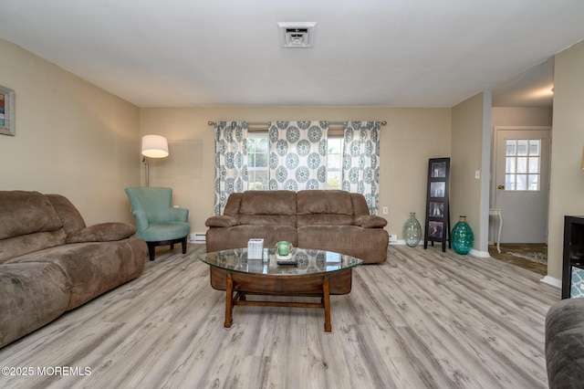 living area with wood finished floors, visible vents, baseboard heating, and baseboards