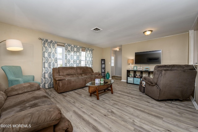 living room featuring visible vents, baseboards, and wood finished floors