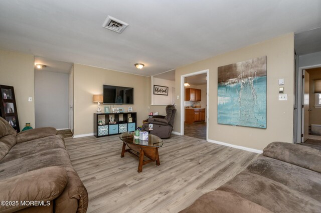 living room featuring visible vents, baseboards, and wood finished floors