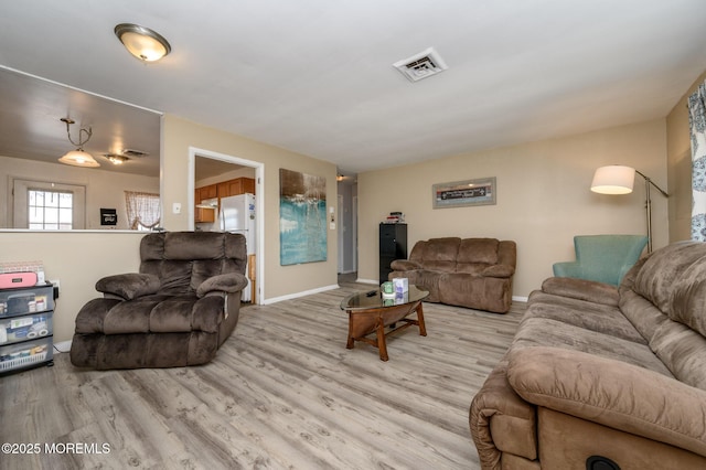 living room with visible vents, baseboards, and light wood-style flooring