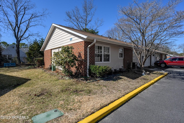 view of front of property featuring central AC, fence, a front yard, a garage, and brick siding