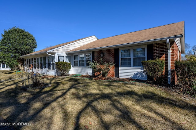 ranch-style home featuring brick siding, a front lawn, and a sunroom