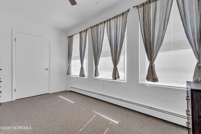 carpeted empty room with a ceiling fan and a baseboard radiator