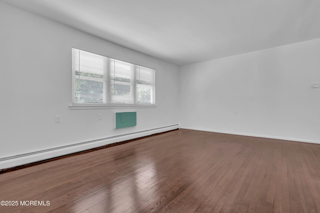 unfurnished room with a baseboard heating unit, baseboards, and wood finished floors