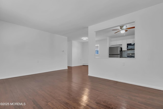 unfurnished living room with ceiling fan, a baseboard heating unit, baseboards, and dark wood finished floors