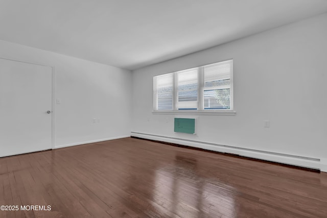 unfurnished room featuring a baseboard heating unit and wood finished floors