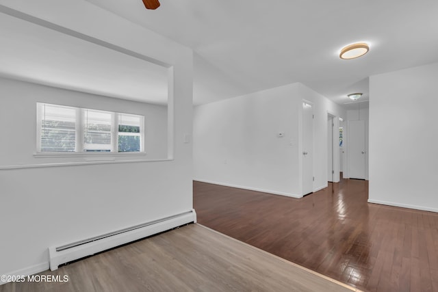 spare room featuring baseboards, baseboard heating, attic access, and wood finished floors