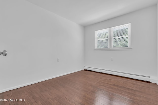 unfurnished room featuring a baseboard heating unit, wood finished floors, and baseboards