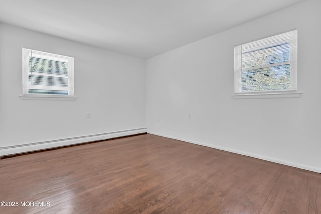 spare room with baseboard heating, baseboards, and wood finished floors