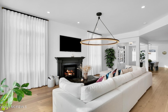 living room featuring a glass covered fireplace, light wood-style flooring, and recessed lighting