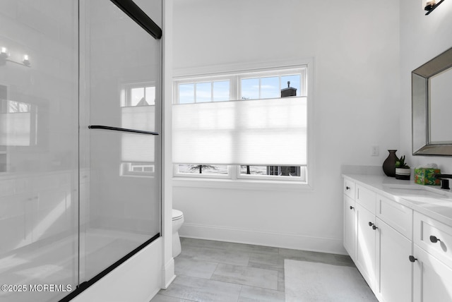 bathroom featuring a shower with door, toilet, vanity, and baseboards