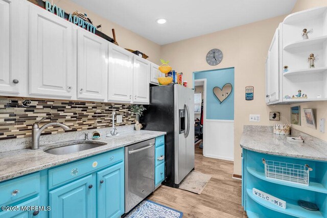 kitchen with open shelves, blue cabinetry, a sink, appliances with stainless steel finishes, and white cabinets