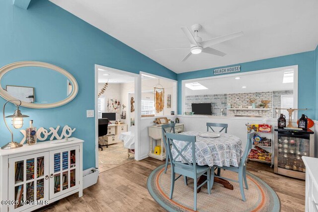 dining space featuring wine cooler, lofted ceiling, wood finished floors, and a ceiling fan