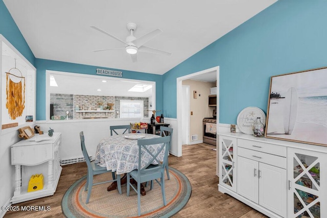 dining area with ceiling fan, wood finished floors, and vaulted ceiling