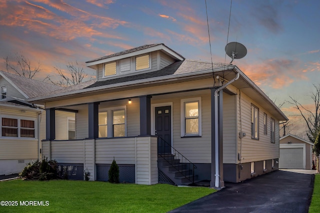 bungalow-style house with driveway, a porch, a yard, an outdoor structure, and a garage