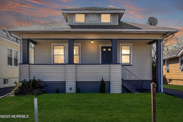 bungalow-style house with stairs, a front yard, covered porch, and roof with shingles