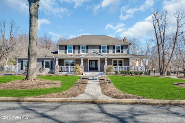 view of front of home featuring covered porch, a chimney, and a front yard